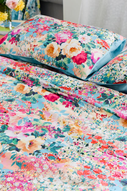 Bộ chăn ga hoa hồng cotton sateen cao cấp cận cảnh vỏ gối nằm phối mầu xanh biển trên nền hoa nhí rực rỡ
