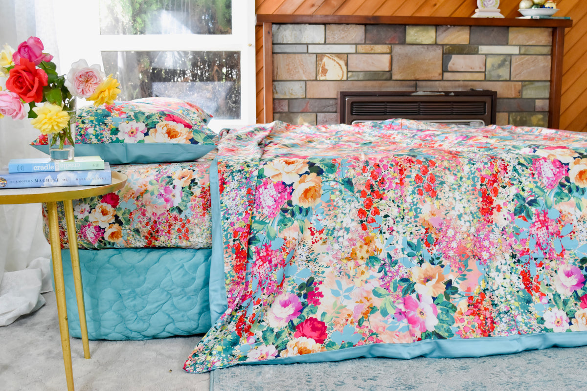 bộ chăn ga cotton cao cấp hoạ tiết hoa nhí phối hoa hồng góc chụp từ bên cạnh chiếu vaò chăn phủ trên đệm chạm xuống dưới sàn, mầu hoa tươi sáng rực rỡ