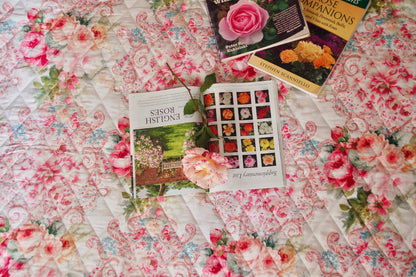 Chăn hè thu cotton hoa cao cấp Victoria Pink Rose góc chụp thẳng từ trên cao, phối cùng cuốn sách mở về hoa hồng Anh Quốc cổ điển và cành hoa tươi lãng mạn
