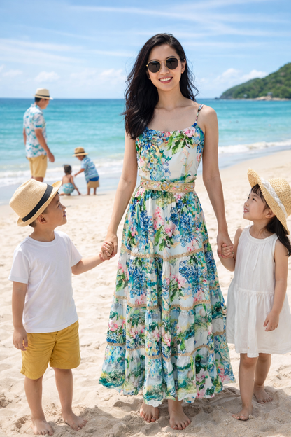 Đầm đi nghỉ dưỡng holiday thiết kế váy maxi hai dây hoa diên vĩ màu xanh mát, hình ảnh phối đồ set gia đình đồng điệu đi chơi trên bãi biển cát trắng
