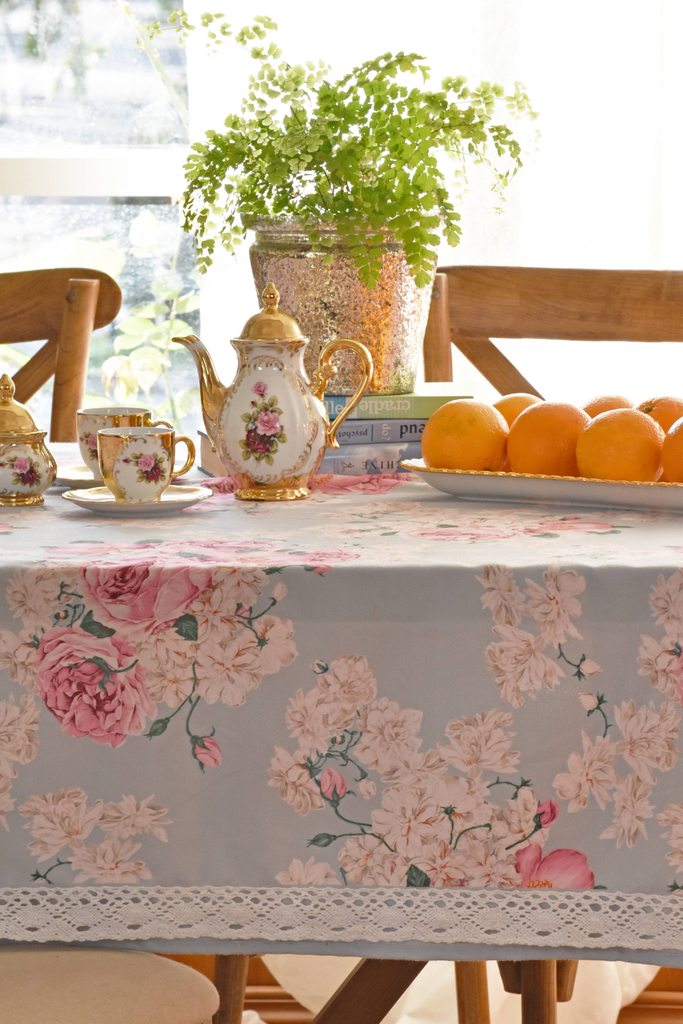 Khăn trải bàn cao cấp vải họa tiết hoa mẫu đơn Rose Peony thiết kế đường viền ren tinh xảo, phối cùng bộ ấm trà sứ cổ điển và rổ trái cây tươi trên bàn ăn gỗ ấm cúng
