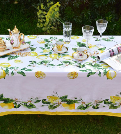 Khăn trải bàn cao cấp vải dáng chữ nhật họa tiết chanh vàng Tuscany Lemon Rose phối cùng bộ ly chén viền mạ vàng châu Âu, ly pha lê sang trọng chụp từ đằng trước lại

